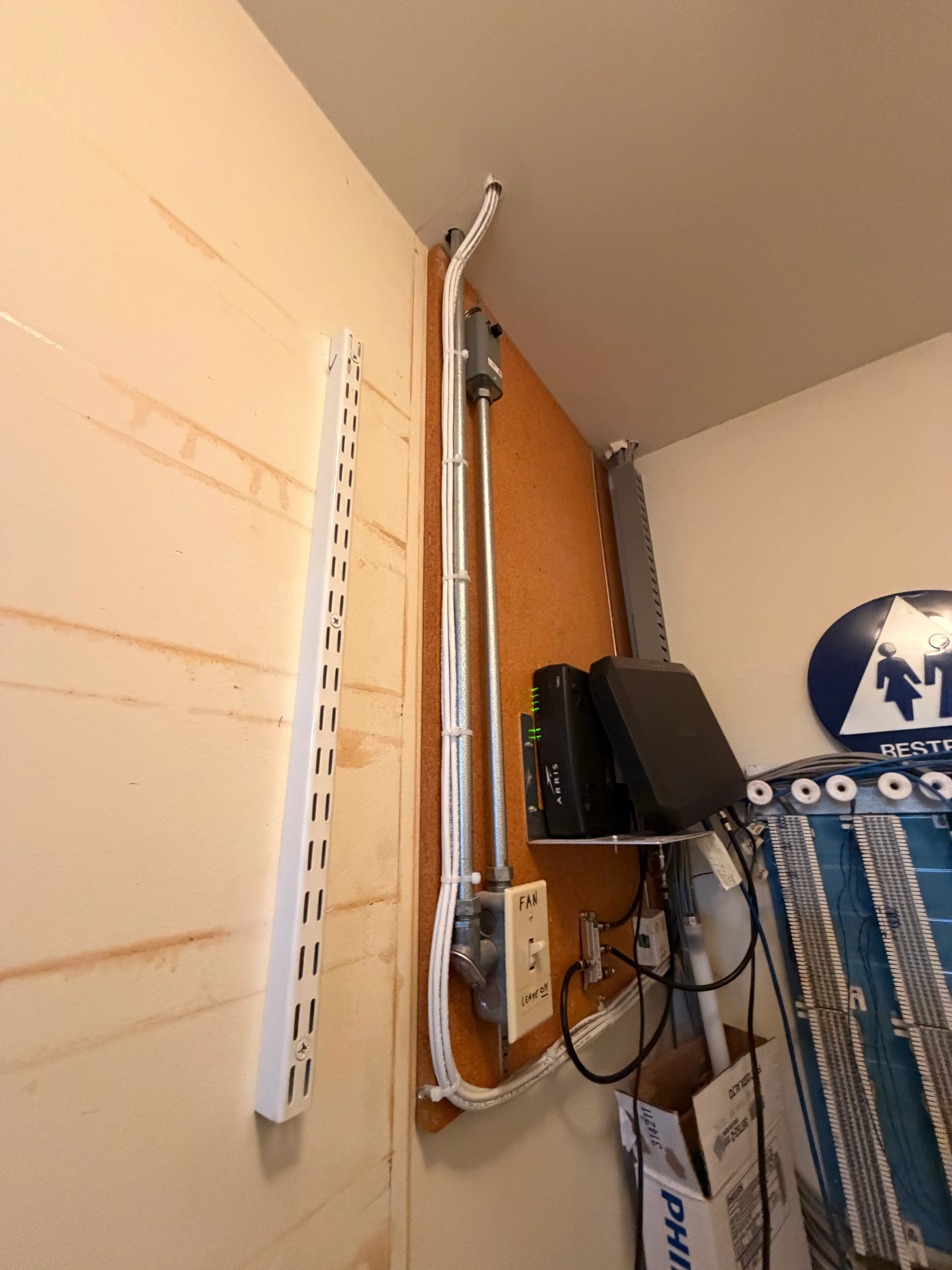 Vertical white PVC conduit installation with outlet boxes mounted on wooden backing plate