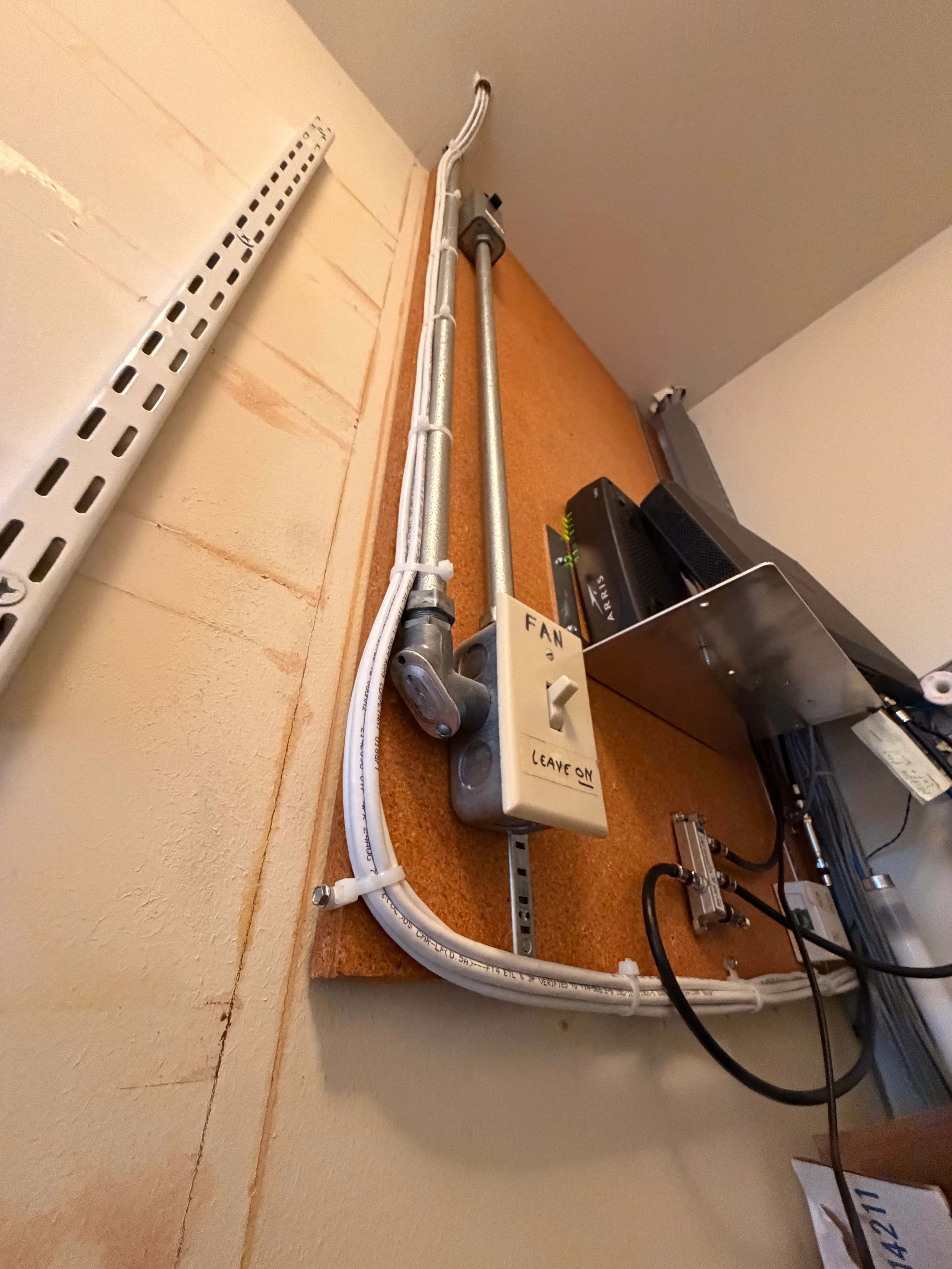 White PVC conduit and telecommunications cables installed on interior wall with metal support hardware