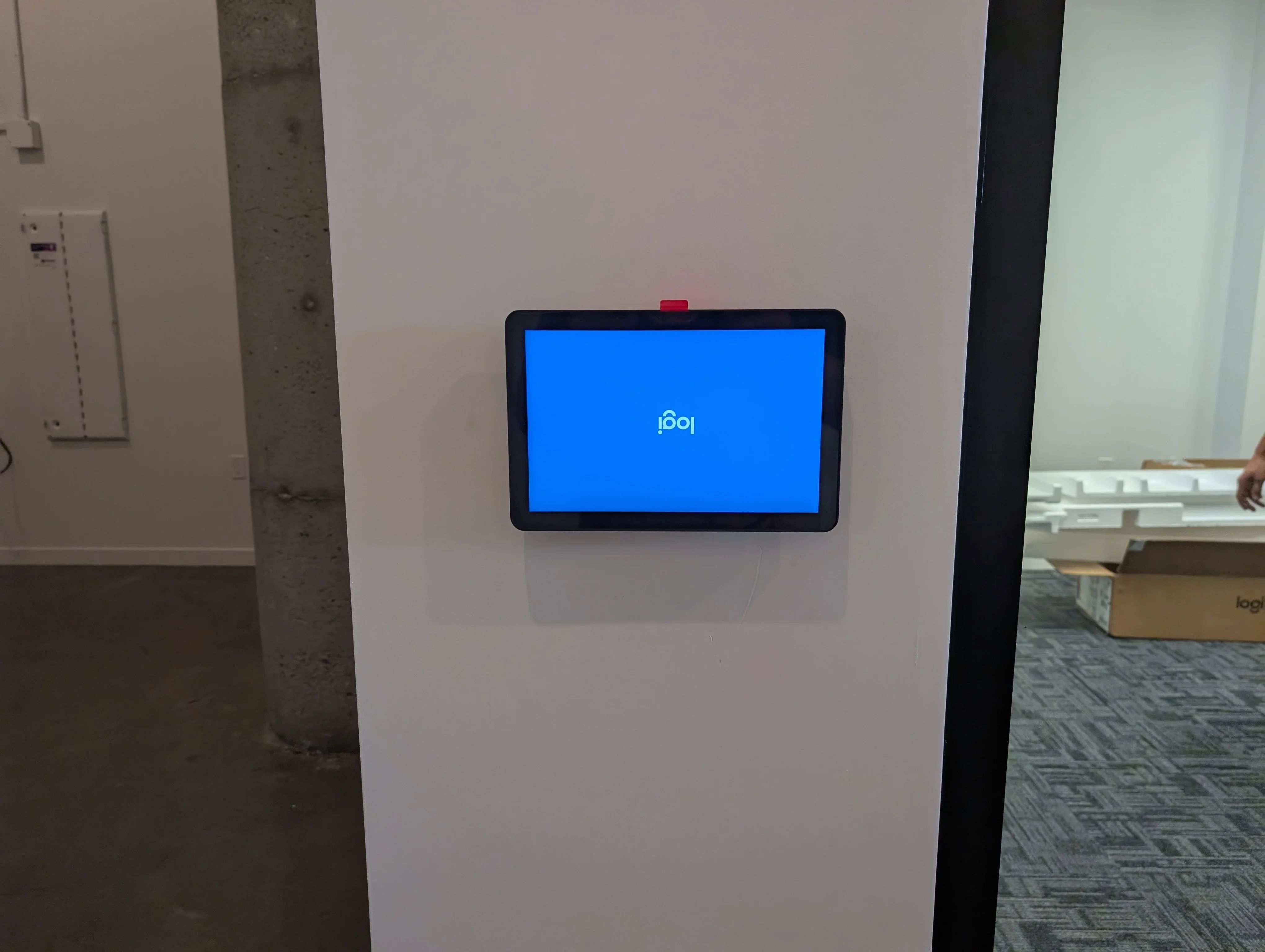 Wall-mounted digital display with black frame showing blue startup screen in commercial space